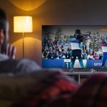 Мужчина смотрит олимпийские игры на телевизоре